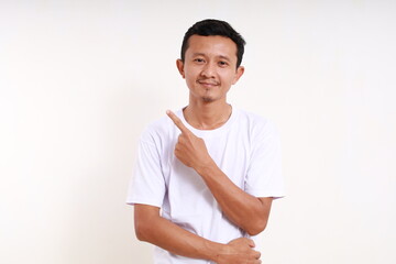 Wall Mural - Happy asian funny man standing while pointing something beside him. Isolated on white