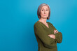 Photo of egoist selfish businesswoman pensioner wear khaki jumper folded hands look empty space arrogant isolated over blue background
