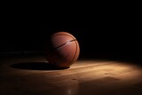 Fototapeta Sport - Basketball staying on top of a wooden floor. Dramatic spot lighting. 