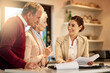 © Alexandra W/peopleimages.com - Senior couple, lawyer and paperwork in discussion for budget or retirement plan at home. Happy elderly man and woman with consultant or financial advisor and documents for investment planning or loan