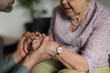 © Halfpoint - Close up of son holding hands of his senior mother, concept of healthcare and relationships.
