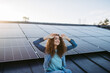 © Halfpoint - Portrait of young woman on roof with solar panels.