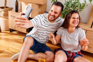 Wall Mural - Couple having fun taking selfies with their new apartment keys while moving in together