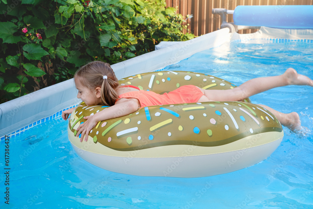 Happy preschool girl in outdoor swimming pool on inflatable ring. Child ...