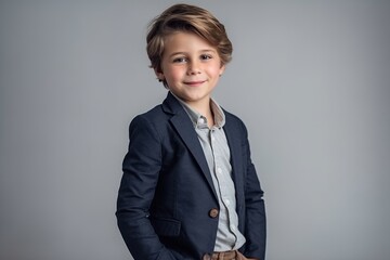 Wall Mural - Portrait of a cute little boy in a suit on a gray background