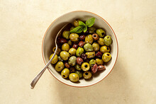 Different color of marinated olives in a bowl, top view
