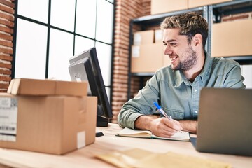 young man ecommerce business worker using laptop writing on notebook at office