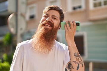 Sticker - Young redhead man smiling confident listening audio message by sthe smartphone at street