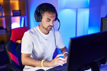 Poster - Young hispanic man streamer playing video game using computer at gaming room