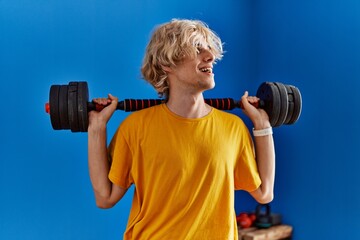 Poster - Young blond man smiling confident using weight training at sport center