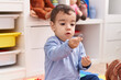 © Krakenimages.com - Adorable hispanic boy sitting on floor with relaxed expression at kindergarten