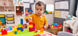 © Krakenimages.com - Adorable hispanic boy playing with construction blocks standing at kindergarten