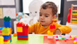 © Krakenimages.com - Adorable hispanic boy playing with construction blocks sitting on table at kindergarten