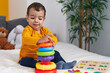 © Krakenimages.com - Adorable hispanic boy playing with hoops game sitting on bed at bedroom
