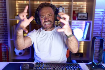 Sticker - Middle age man with beard playing video games wearing headphones shouting frustrated with rage, hands trying to strangle, yelling mad