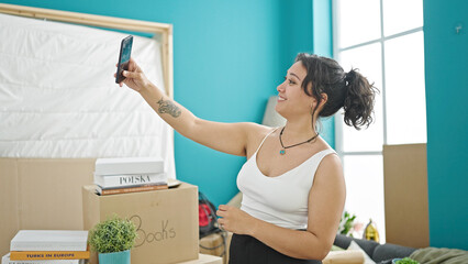 Poster - Young beautiful hispanic woman make selfie by smartphone smiling at new home