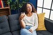 © Krakenimages.com - Young latin woman drinking champagne sitting on sofa at home