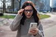 © Andrei - Shocked woman receiving a scam call holding her eyeglasses