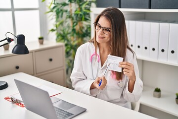 Canvas Print - Young beautiful hispanic woman doctor pointing to covid certificate card at clinic