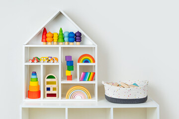 Wall Mural - White house shaped shelving with colorful wooden toys on white wall. Interior design. Organizing and Storage Ideas in nursery.