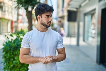 Wall Mural - Young hispanic man with relaxed expression standing at street