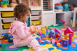 © Krakenimages.com - Adorable hispanic girl playing with construction blocks sitting on floor at kindergarten