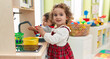 © Krakenimages.com - Adorable girls playing with play kitchen standing at kindergarten