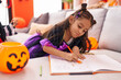 © Krakenimages.com - Adorable hispanic girl drawing on notebook having halloween party at home