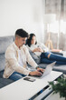 © ADDICTIVE STOCK - Young man working on sofa with laptop near woman with mobile phone in living room
