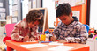 © Krakenimages.com - Adorable african american boy and girl preschool students sitting on table drawing on paper at kindergarten