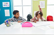 © Krakenimages.com - Adorable african american boy and girl students sitting on table with finger raised up at classroom