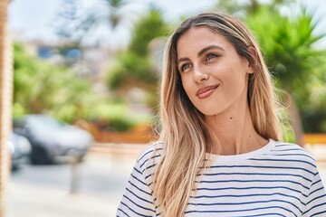 Wall Mural - Young blonde woman smiling confident looking to the side at street