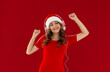 Funny young woman wearing green hoodie Christmas hat listening music with headphones keeping eyes closed isolated on red background studio portrait. Happy New Year celebration merry holiday concept