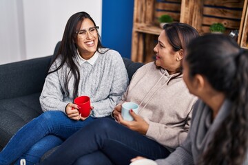 Wall Mural - Three woman drinking coffee sitting on sofa at home