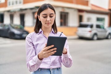 Wall Mural - Young hispanic woman using touchpad at street