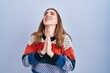 © Krakenimages.com - Young hispanic girl standing over blue background begging and praying with hands together with hope expression on face very emotional and worried. begging.