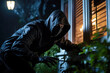 Burglar breaking into a house, home invasion, thief, burglary, masked, hood, security and insurance concept