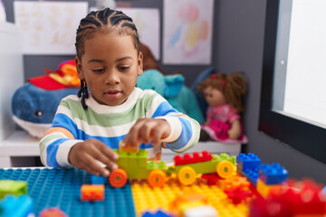 African american boy playing with construction blocks sitting on table at kindergarten