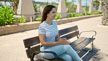 Middle eastern woman sitting on a bench with serious expression at park