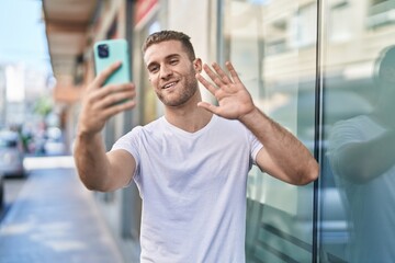 Wall Mural - Young caucasian man smiling confident having video call at street