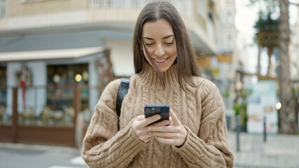 Wall Mural - Young beautiful hispanic woman using smartphone smiling at coffee shop terrace