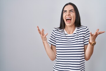 Wall Mural - Young brunette woman wearing striped t shirt celebrating mad and crazy for success with arms raised and closed eyes screaming excited. winner concept