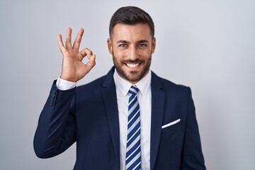 Poster - Handsome hispanic man wearing suit and tie smiling positive doing ok sign with hand and fingers. successful expression.