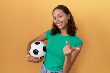 Sticker - Young hispanic woman holding ball beckoning come here gesture with hand inviting welcoming happy and smiling