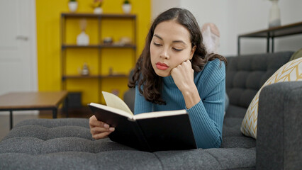 Sticker - Young beautiful hispanic woman reading book lying on sofa at home