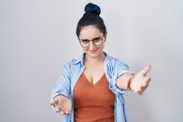 Sticker - Young modern girl with blue hair standing over white background smiling cheerful offering hands giving assistance and acceptance.