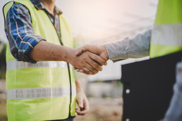 Wall Mural - construction worker and contractor. Client shaking hands with team builder in the factory construction site.