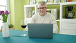 © Krakenimages.com - Middle age grey-haired man drinking glass of wine using laptop at home