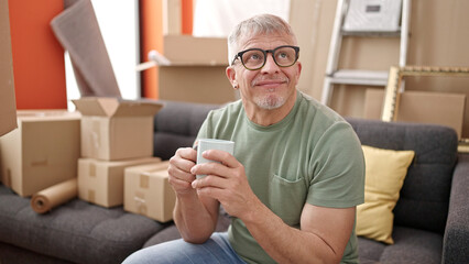 Poster - Middle age grey-haired man smiling confident drinking coffee at new home