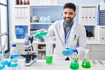 Sticker - Young hispanic man wearing scientist uniform measuring liquid at laboratory